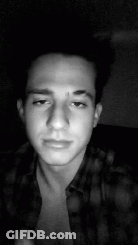 A Black And White Photo Of A Young Man Wearing A Plaid Shirt And Looking At The Camera . GIF
