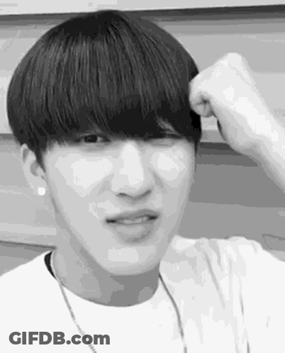 A Black And White Photo Of A Young Man With A Bangs Holding His Hair . GIF