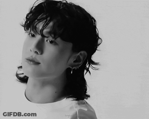 A Black And White Photo Of A Young Man With A Ponytail GIF