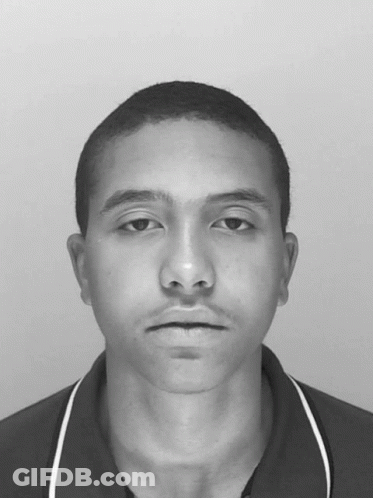 A Black And White Photo Of A Young Man With A Shaved Head GIF