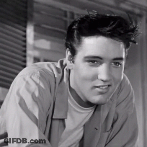 A Black And White Photo Of A Young Man With A Slight Smile On His Face GIF