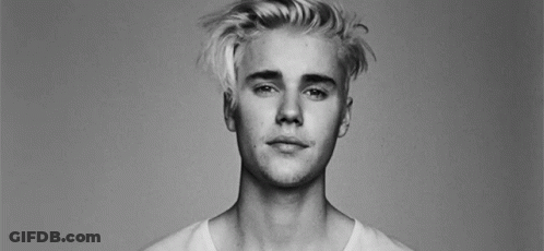 A Black And White Photo Of A Young Man With Blonde Hair And A White Shirt . GIF
