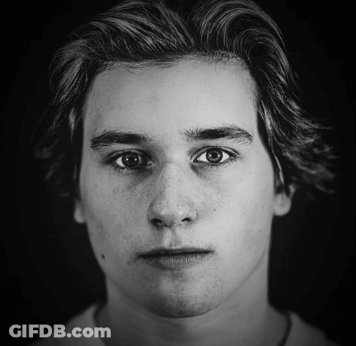 A Black And White Photo Of A Young Man With Freckles GIF