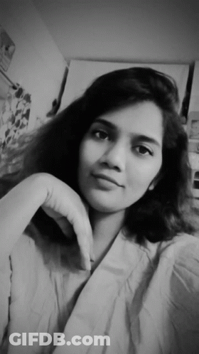 A Black And White Photo Of A Young Woman With Her Hand On Her Chin GIF