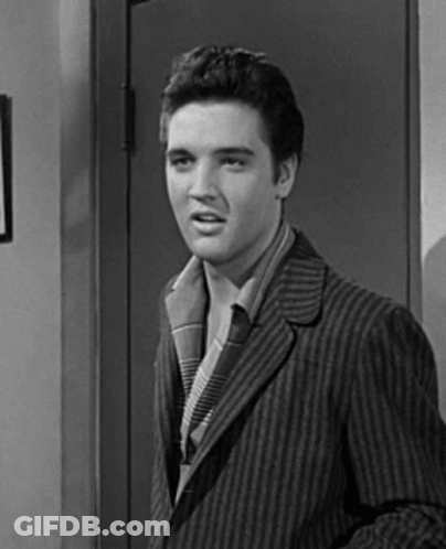 A Black And White Photo Of Elvis Presley In A Striped Suit Standing In Front Of A Door . GIF