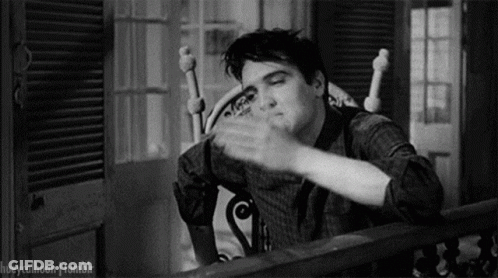 A Black And White Photo Of Elvis Presley Sitting In A Rocking Chair And Waving His Hand . GIF
