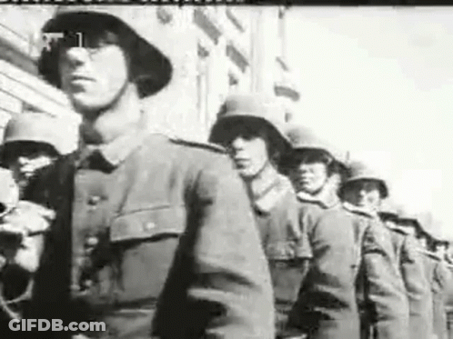 A Black And White Photo Of Soldiers Marching In A Line . GIF