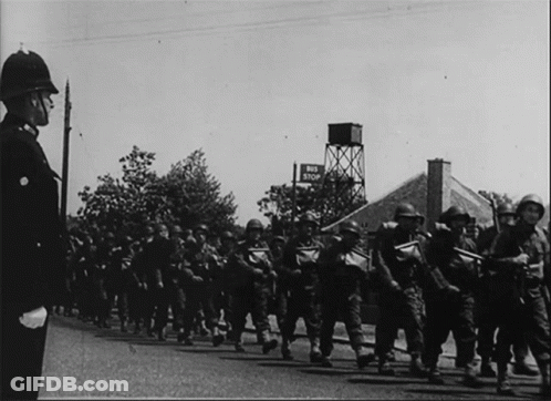 A Black And White Photo Of Soldiers Marching In Front Of A Sign That Says End Stop GIF