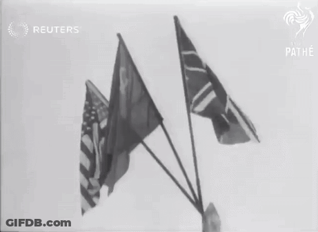A Black And White Photo Of Three Flags With The Reuters Logo In The Background GIF