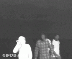A Black And White Photo Of Three People Standing Next To Each Other In A Dark Room . GIF