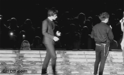 A Black And White Photo Of Two Men Dancing On A Stage . GIF