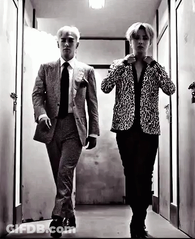 A Black And White Photo Of Two Men In Suits And Ties Walking Down A Hallway . GIF