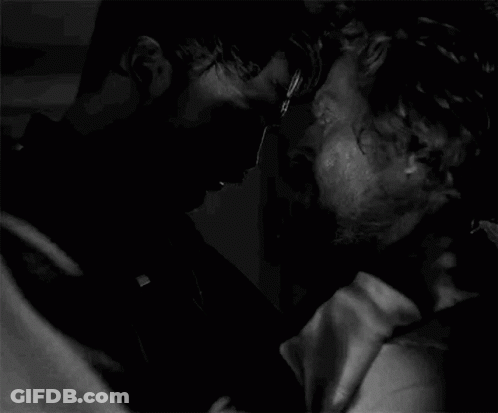 A Black And White Photo Of Two Men Kissing Each Other In A Dark Room . GIF