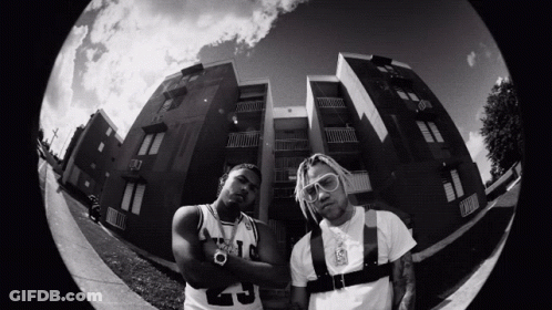 A Black And White Photo Of Two Men Standing In Front Of A Building With One Wearing A Number 9 Jersey GIF