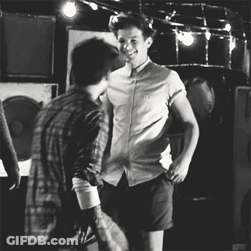 A Black And White Photo Of Two Men Standing Next To Each Other And Smiling . GIF