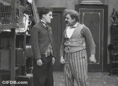 A Black And White Photo Of Two Men Standing Next To Each Other In A Room GIF