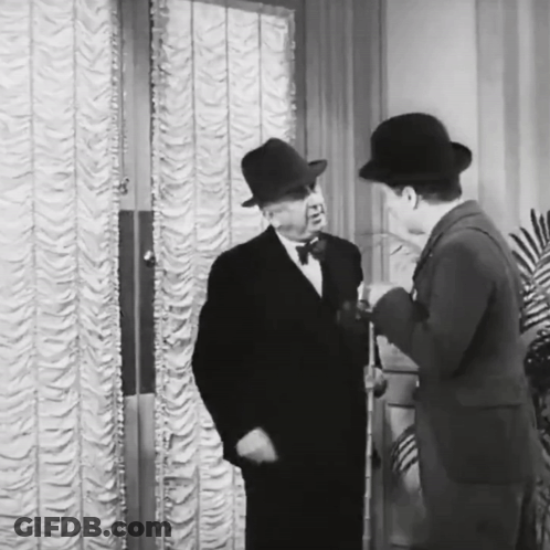A Black And White Photo Of Two Men Talking GIF