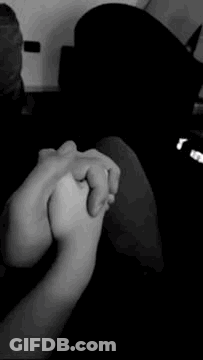 A Black And White Photo Of Two People Holding Hands . GIF