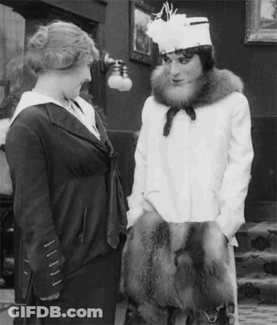 A Black And White Photo Of Two Women Talking To Each Other . One Of The Women Is Wearing A Fur Coat . GIF