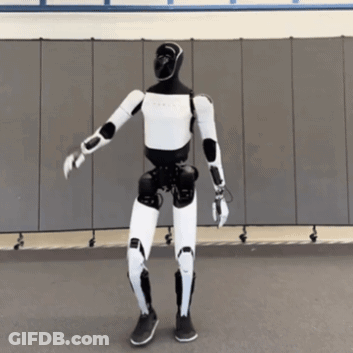 A Black And White Robot Is Dancing In Front Of A Gray Wall GIF