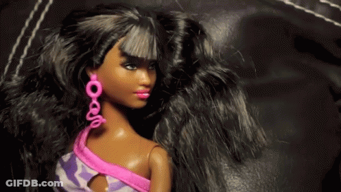 A Black Barbie Doll Wearing Pink Earrings And A Purple Top GIF
