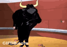 A Black Bull With Horns Is Standing In A Bullring . GIF