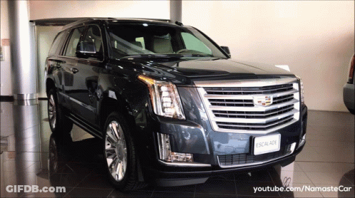 A Black Cadillac Escalade Is In A Showroom GIF