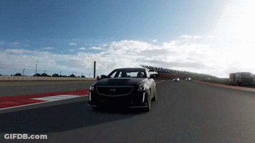 A Black Cadillac Is Driving Down A Track GIF