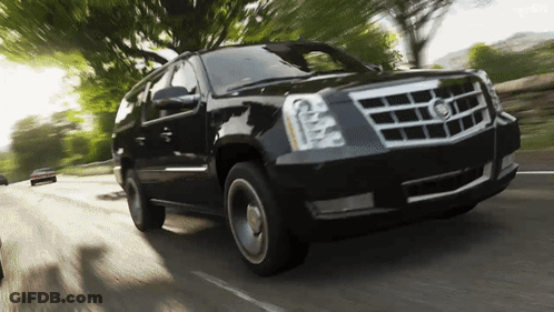 A Black Cadillac Suv Is Driving Down The Road GIF