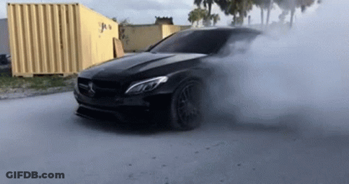 A Black Car Is Drifting And Smoke Is Coming Out Of It 'S Tire GIF