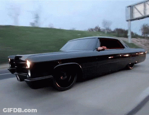 A Black Car Is Driving Down A Highway With A Billboard In The Background GIF