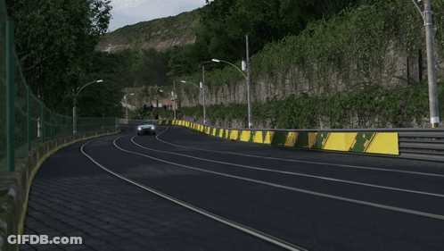 A Black Car Is Driving Down A Road Next To A Wall GIF