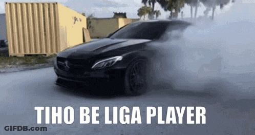 A Black Car Is Driving Down A Street With Smoke Coming Out Of It And The Words Tho Be Liga Player GIF