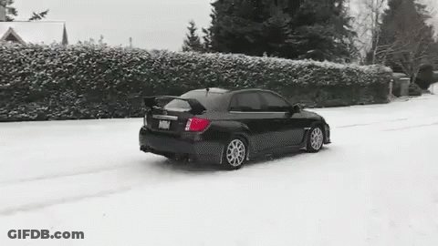 A Black Car Is Driving In The Snow On A Snowy Road . GIF
