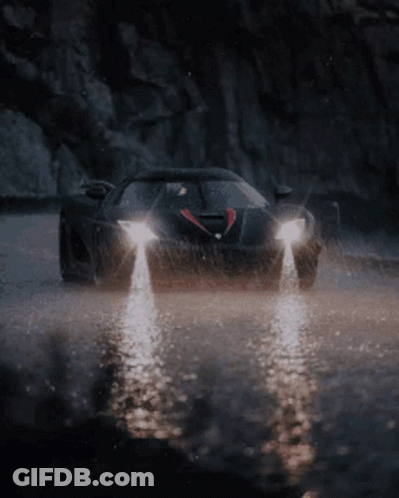 A Black Car Is Driving Through A Puddle Of Water GIF