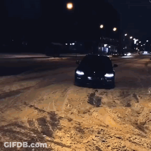 A Black Car Is Driving Through The Snow At Night GIF