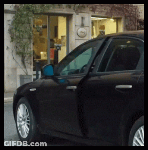 A Black Car Is Parked In Front Of A Building With A Sign That Says ' I ' On It GIF