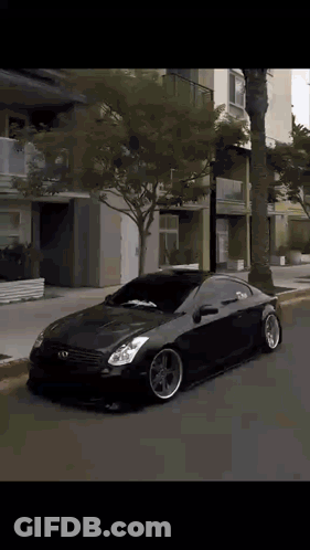 A Black Car Is Parked On The Side Of A Street GIF