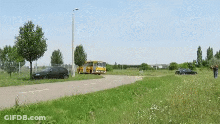 A Black Car Is Parked On The Side Of The Road Next To A Bus GIF
