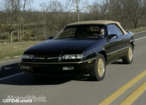A Black Car With A Tan Top Is Driving Down A Road With Motorweek Written On The Bottom GIF