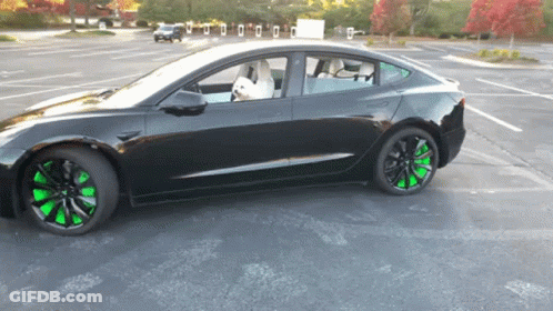 A Black Car With Green Wheels Is Parked In A Lot GIF