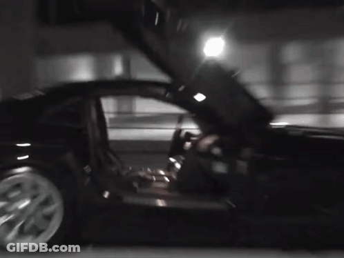 A Black Car With Its Doors Open Is Parked In A Parking Lot At Night . GIF