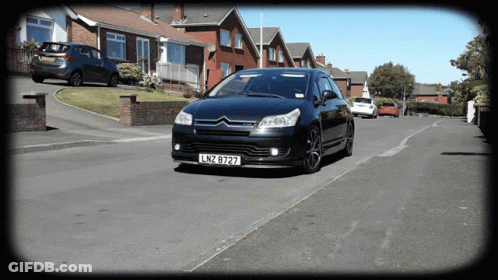 A Black Car With License Plate Lnz 8727 Is Driving Down A Street GIF