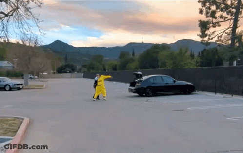 A Black Car With The Trunk Open Is Parked In A Parking Lot With Mountains In The Background GIF