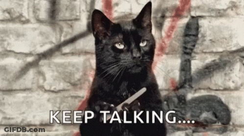 A Black Cat Is Holding A Pair Of Scissors In Front Of A Brick Wall . GIF