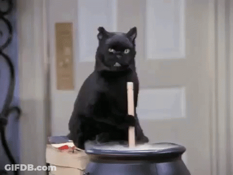 A Black Cat Is Sitting On Top Of A Black Cauldron . GIF
