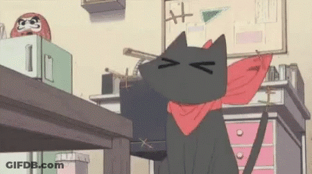 A Black Cat Wearing A Red Scarf Around Its Neck Is Sitting On A Desk . GIF
