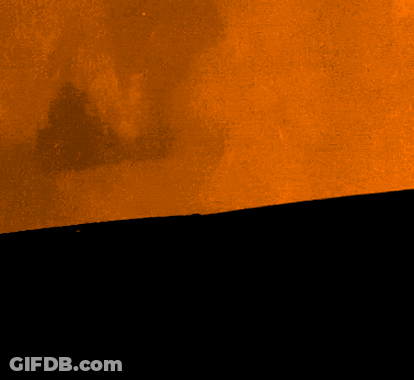 A Black Cat With Bright Yellow Eyes Is Peeking Out From Behind A Wall GIF