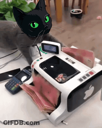 A Black Cat With Green Eyes Sits Next To A Machine That Has An Apple Logo GIF
