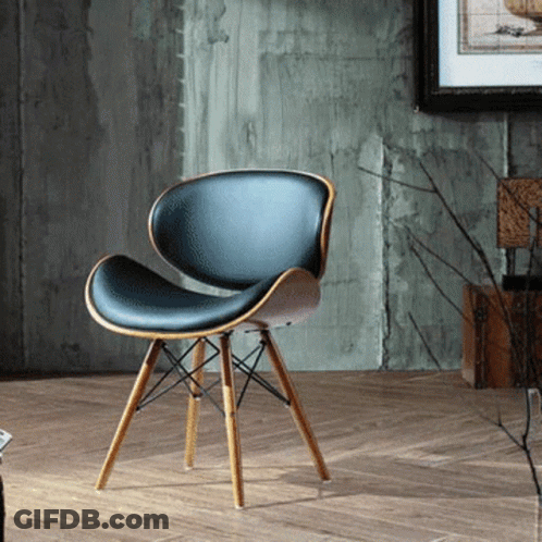 A Black Chair With Wooden Legs Is Sitting On A Wooden Floor GIF